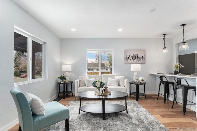 living area with baseboards, wood finished floors, and recessed lighting