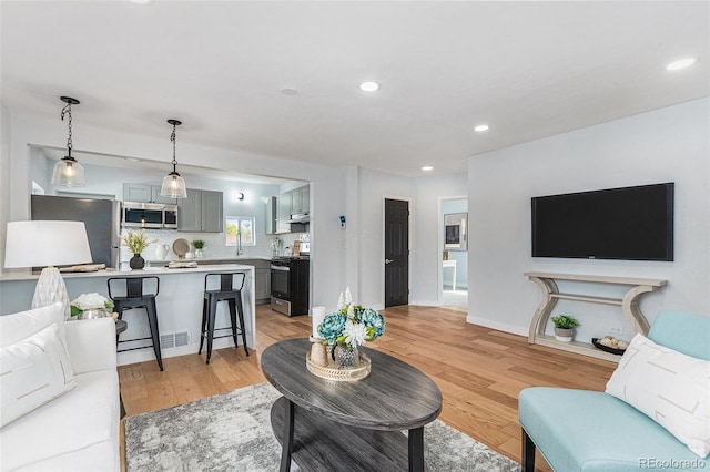 living area with light wood-style floors, recessed lighting, and baseboards