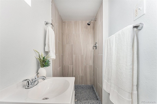bathroom featuring a tile shower and a sink