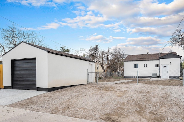 detached garage featuring fence, driveway, and a gate