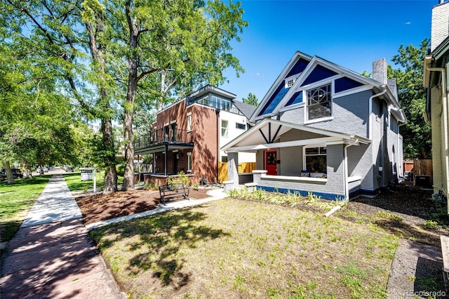 rear view of property featuring a balcony, a porch, and a lawn