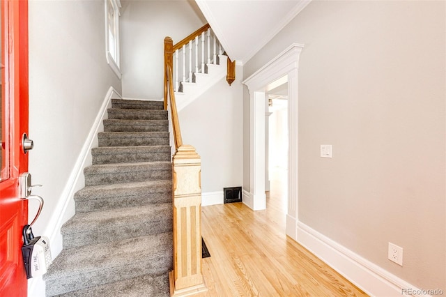 stairway featuring ornamental molding and wood-type flooring