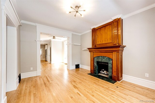 unfurnished living room with a high end fireplace, decorative columns, crown molding, and light wood finished floors