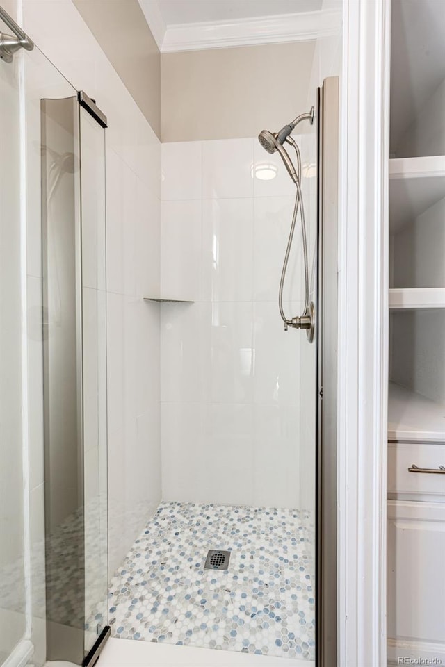 bathroom with a shower with shower door and ornamental molding