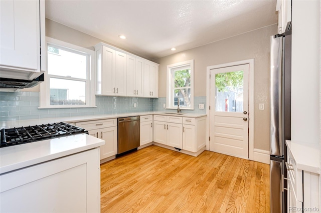 kitchen featuring light hardwood / wood-style flooring, stainless steel appliances, decorative backsplash, and white cabinets