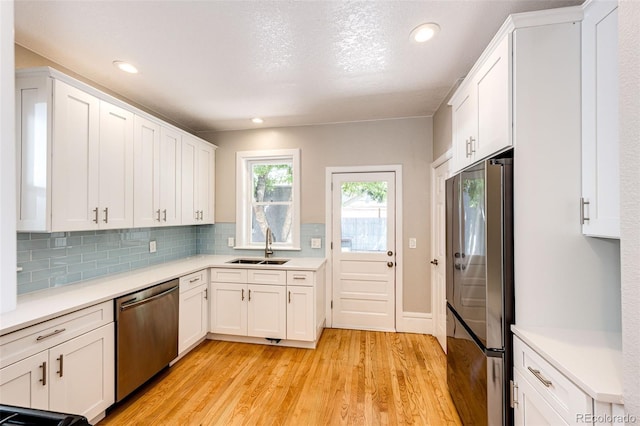 kitchen featuring appliances with stainless steel finishes, sink, white cabinetry, and light hardwood / wood-style flooring