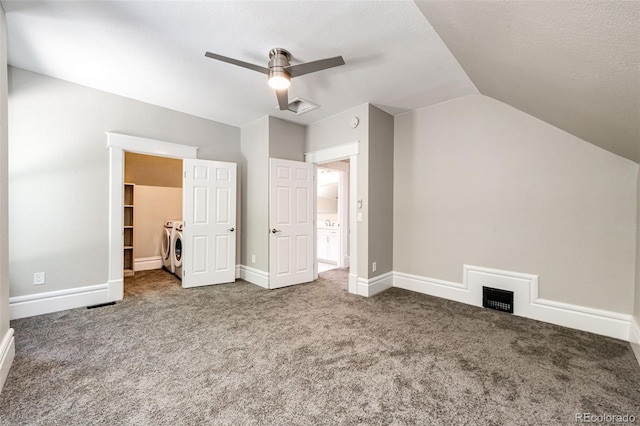 interior space featuring a textured ceiling, washing machine and clothes dryer, ceiling fan, vaulted ceiling, and carpet floors