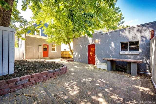 view of front facade with a patio area, stucco siding, and fence