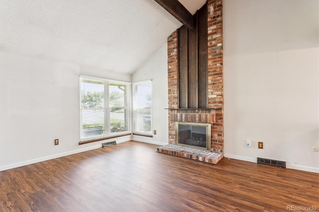 7713 E Jamison Dr, Centennial, CO 80112 - unfurnished living room featuring beam ceiling, wood finished floors, a brick fireplace, high vaulted ceiling, and a textured ceiling