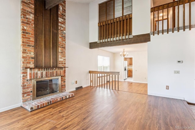7713 E Jamison Dr, Centennial, CO 80112 - unfurnished living room with a high ceiling, a chandelier, wood finished floors, and a brick fireplace