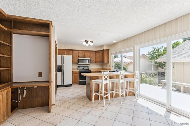 7713 E Jamison Dr, Centennial, CO 80112 - kitchen featuring white fridge with ice dispenser, stainless steel microwave, black range with electric stovetop, light countertops, and light tile patterned floors
