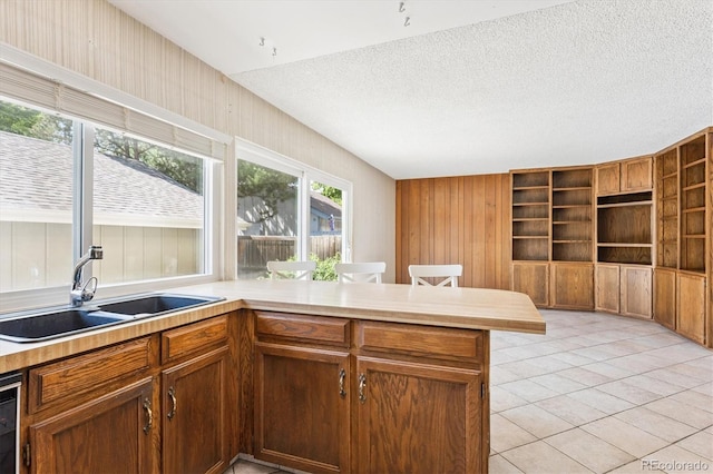 7713 E Jamison Dr, Centennial, CO 80112 - kitchen featuring a peninsula, light countertops, a textured ceiling, light tile patterned flooring, and wood walls
