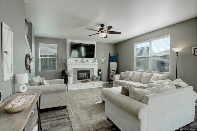 975 Alta St, Lochbuie, CO 80603 - living room featuring a ceiling fan, a glass covered fireplace, and dark wood-style flooring