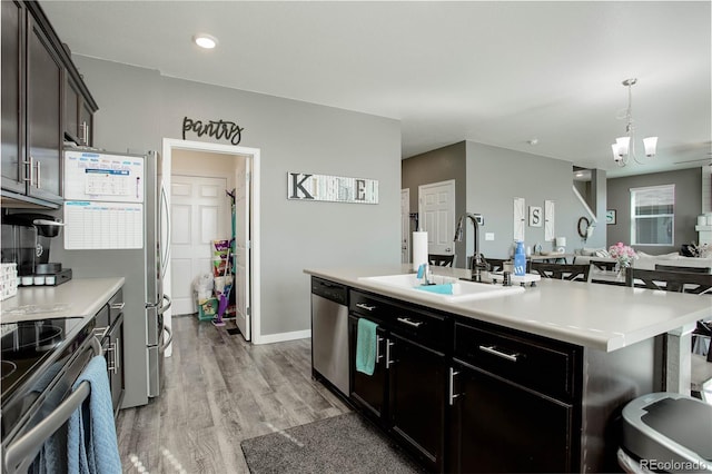 975 Alta St, Lochbuie, CO 80603 - kitchen with appliances with stainless steel finishes, a sink, light countertops, a center island with sink, and light wood-type flooring