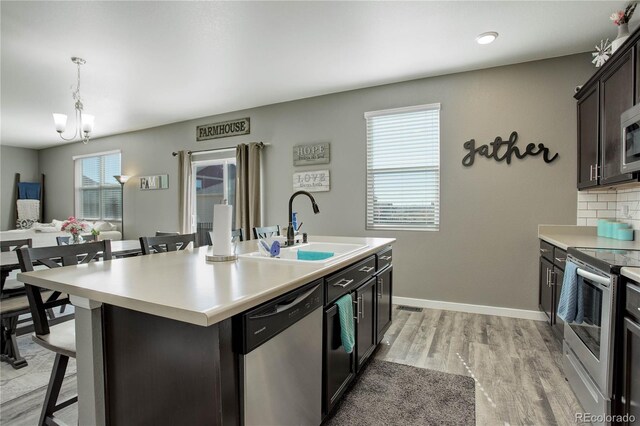 975 Alta St, Lochbuie, CO 80603 - kitchen with appliances with stainless steel finishes, a sink, a kitchen breakfast bar, a chandelier, and light wood-type flooring