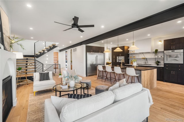 living room with light wood-type flooring, ceiling fan, and sink