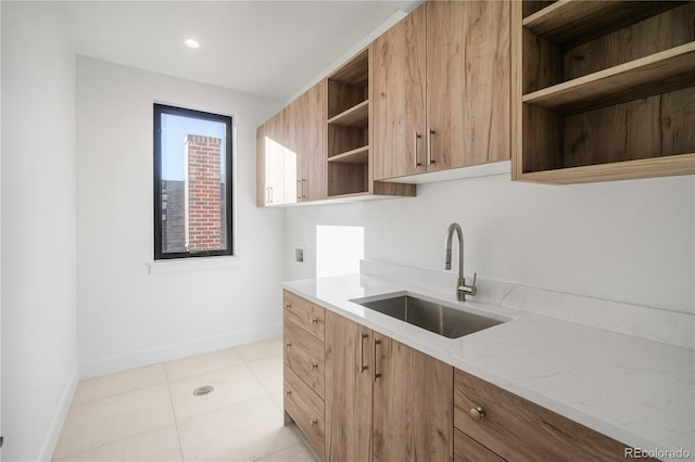 kitchen with light stone counters, light tile patterned floors, and sink