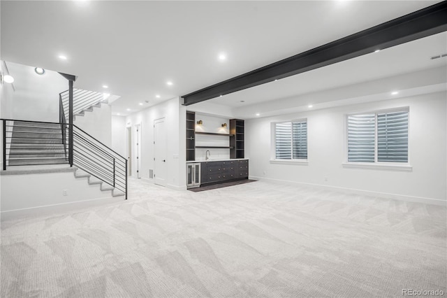 unfurnished living room with beamed ceiling, indoor wet bar, and light carpet