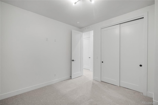 unfurnished bedroom with light colored carpet and a closet