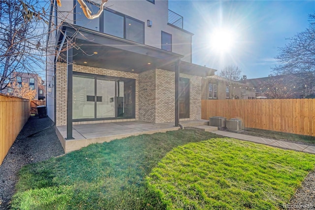 back of house with central AC, a patio area, and a lawn