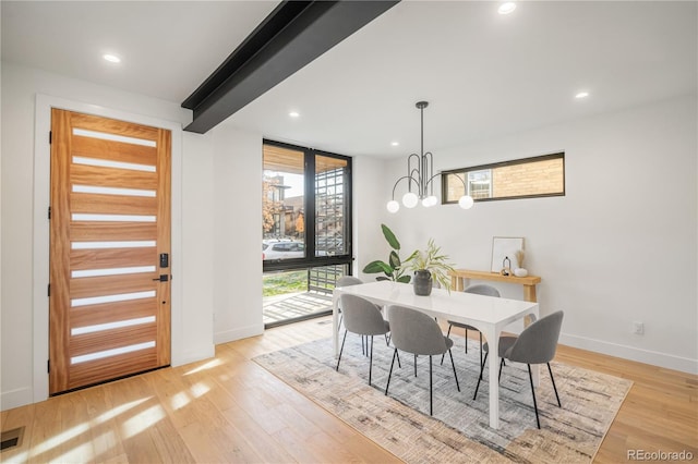 dining area with beamed ceiling, a chandelier, and light wood-type flooring