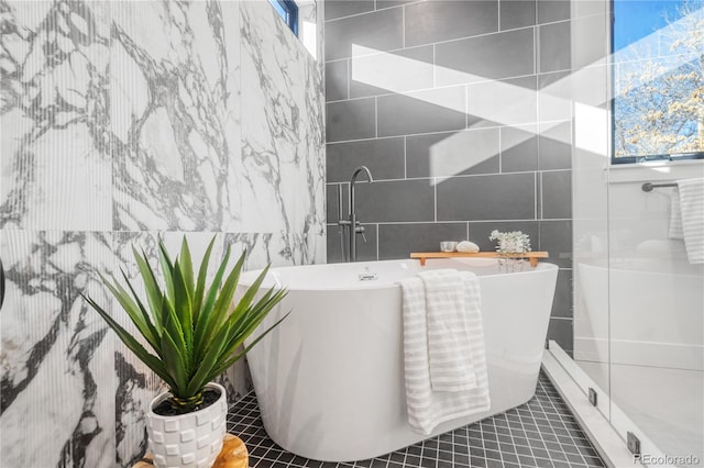 bathroom with a bathing tub, tile patterned flooring, and tile walls