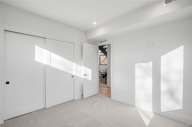 unfurnished bedroom with a closet and light colored carpet