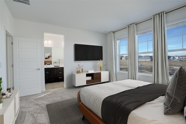 bedroom with connected bathroom and light colored carpet