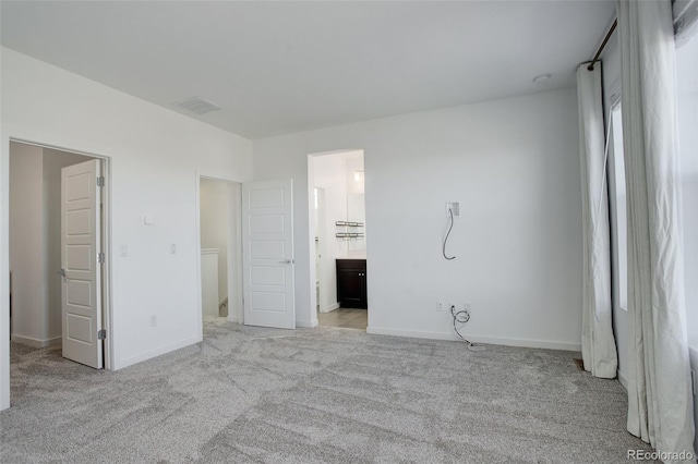 unfurnished bedroom with ensuite bathroom and light carpet