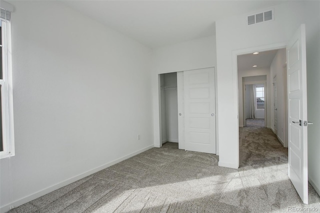 unfurnished bedroom featuring light carpet and a closet