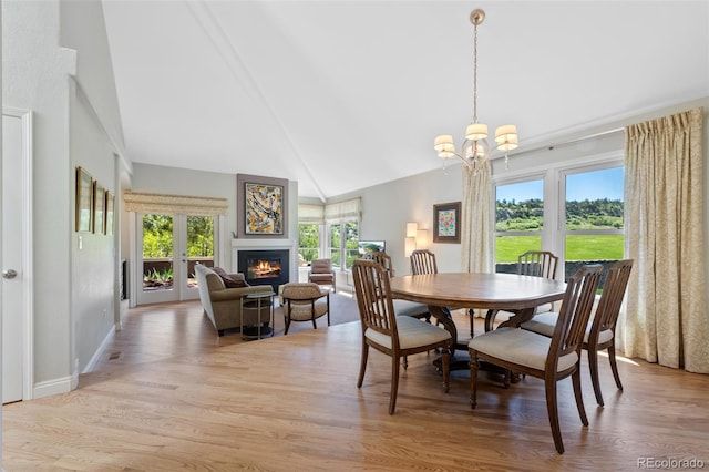 dining area featuring high vaulted ceiling, hardwood / wood-style flooring, and an inviting chandelier