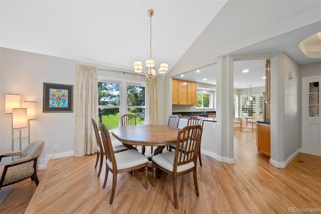 dining room with sink, a chandelier, light hardwood / wood-style floors, and lofted ceiling