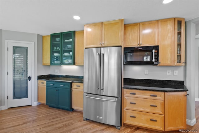 kitchen with dark stone counters, built in fridge, and light wood-type flooring