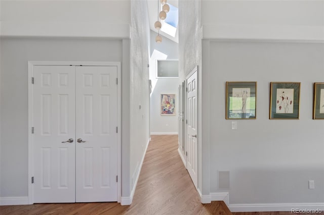 hallway with light hardwood / wood-style flooring and a skylight