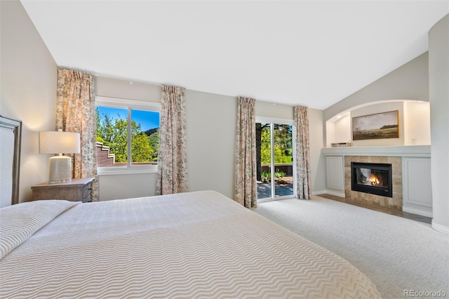 bedroom with carpet flooring, a tiled fireplace, multiple windows, and access to exterior