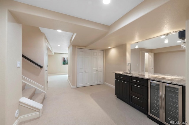 bar featuring light colored carpet, wine cooler, light stone counters, and sink