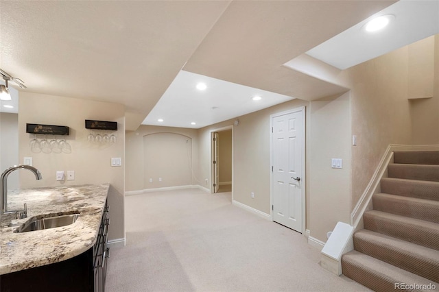 kitchen featuring sink, light stone counters, and light colored carpet