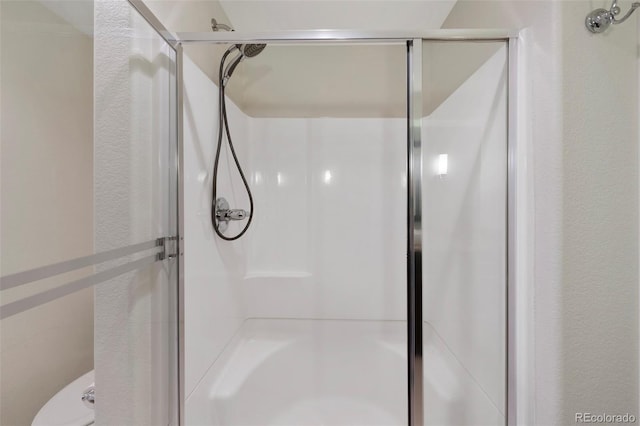 bathroom featuring walk in shower and toilet