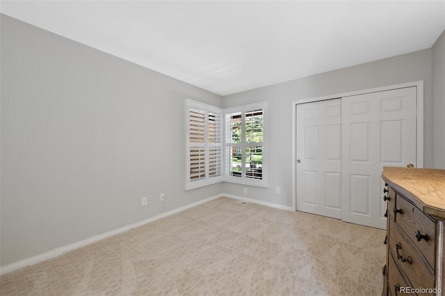 unfurnished bedroom with light carpet and a closet