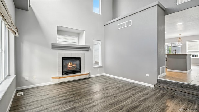 4458 Lyndenwood Pt, Highlands Ranch, CO 80130 - unfurnished living room with wood finished floors, a fireplace, healthy amount of natural light, and a high ceiling