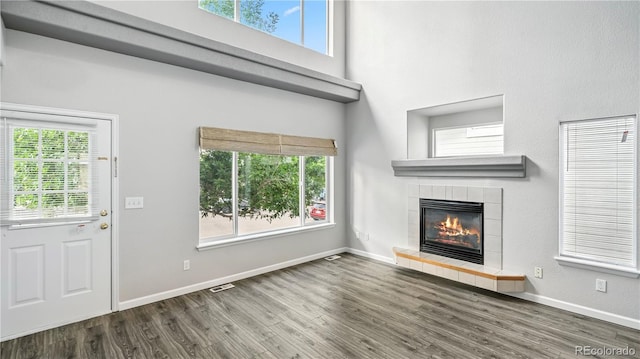 4458 Lyndenwood Pt, Highlands Ranch, CO 80130 - unfurnished living room with wood finished floors, a tiled fireplace, and a high ceiling