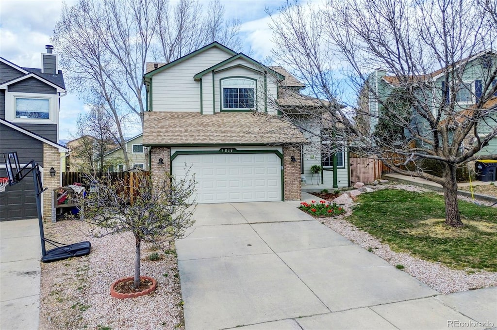 traditional home featuring brick siding, a garage, fence, and concrete driveway