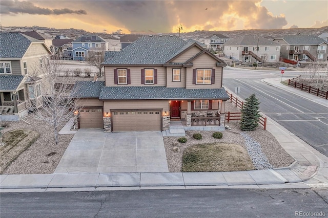 view of front of house with concrete driveway, stone siding, covered porch, an attached garage, and a residential view