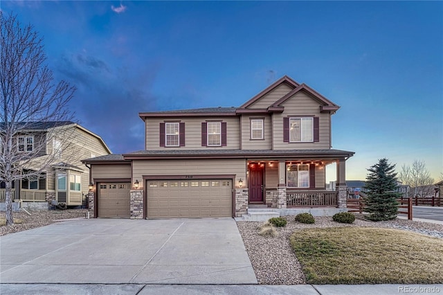 view of front of house with driveway, a porch, stone siding, and fence