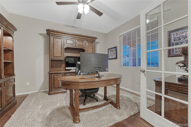 home office with a ceiling fan, baseboards, and dark wood-style floors