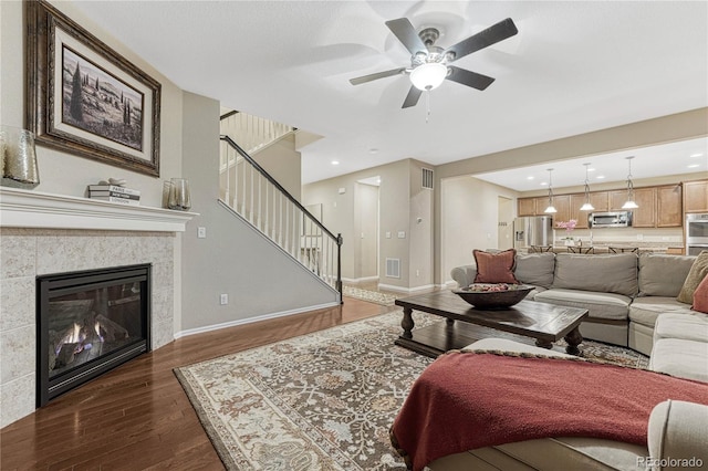 living room with stairway, ceiling fan, baseboards, dark wood-type flooring, and visible vents