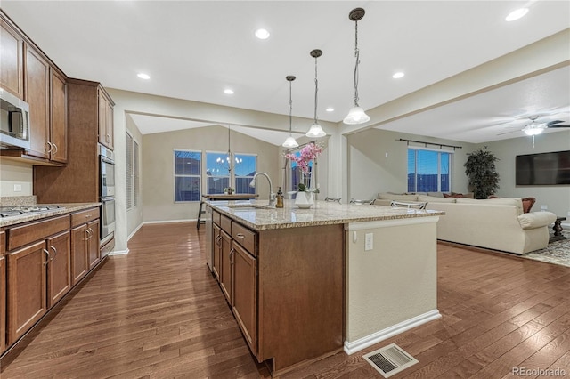 kitchen with dark wood-style floors, a sink, stainless steel appliances, light stone countertops, and visible vents