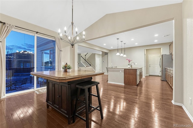 kitchen featuring vaulted ceiling, dark wood-style flooring, a kitchen island with sink, and light countertops