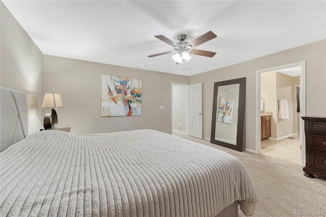 bedroom featuring light colored carpet, ceiling fan, baseboards, and connected bathroom
