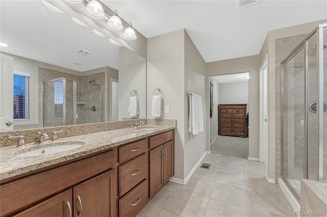 bathroom with visible vents, a sink, a textured ceiling, and a stall shower